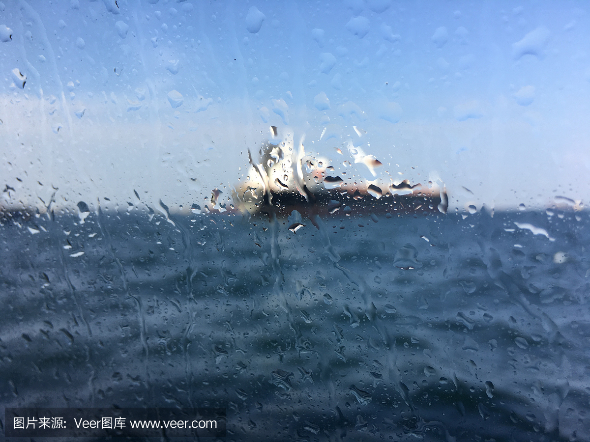 在潮濕的窗戶后面的海上油輪背景模糊圖像